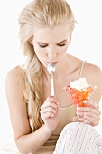 Blond woman eating fruit jelly with cream