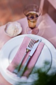 Place-setting and glass of wine on pink chair