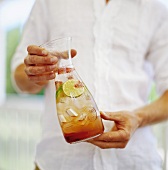 Man holding carafe containing fruity drink