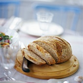 Partly-sliced bread on breadboard