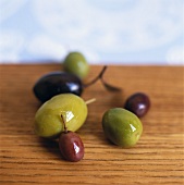 Green and black olives on wooden table