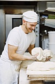 Baker shaping dough in bakery