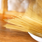 Uncooked spaghetti falling into a deep plate