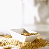 Small white dish on a heap of sesame seeds