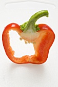 Slice of red pepper with stalk on chopping board
