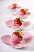Strawberries dipped in pink icing on heart-shaped plates