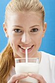 Junge Frau trinkt Milch mit Strohhalm