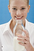 Junge Frau hält eine Milchflasche
