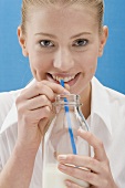 Young woman drinking milk from the bottle with a straw