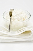 Cottage cheese in small glass bowl with spoon on cloth
