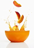 Peach slices falling into fruit juice