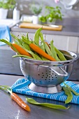 Fresh carrots and beans in a colander