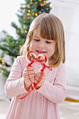 Little girl holding candy canes together to make a heart
