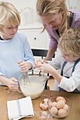 Woman and two boys baking together