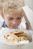 Boy looking at chocolate chip cookies in biscuit tin