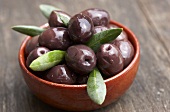 Black olives with leaves in bowl