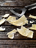 Parmesan shavings with cheese slicer on wooden background