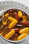 Assorted vitamin capsules and tape measure (close-up)