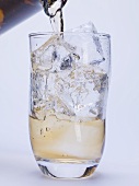 Pouring spirit into glass of ice cubes