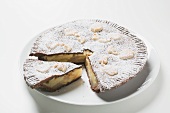 Apple pie dusted with icing sugar, a piece cut