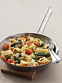 Pasta with pork, spinach and tomatoes in frying pan