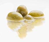 Four green olives in water