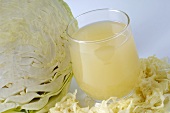 A glass of sauerkraut juice and fresh white cabbage