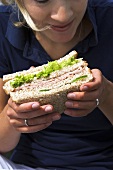 Junge Frau beisst in ein Sandwich