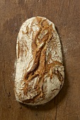 A rustic loaf of sourdough bread on wooden background