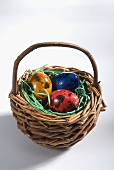 Three coloured Easter eggs in a small basket