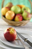 A nectarine on a plate in front of a fruit basket