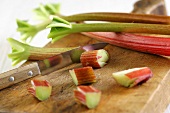 Rhubarb, partly sliced, on chopping board