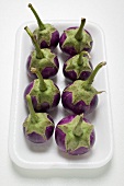 Eight baby aubergines in polystyrene tray