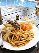 Plate of barbecued food and chips on table by swimming pool