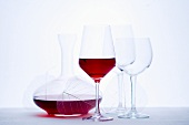Glass of red wine, carafe and empty wine glasses