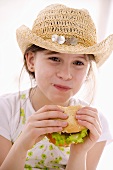Girl in hat eating home-made hamburger