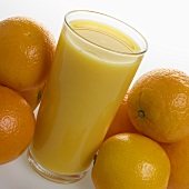 A glass of orange juice with fresh oranges