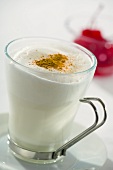 A glass of hot milk with honey, frothed milk and cinnamon