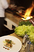 Gegrillter Fisch, Hintergrund: Koch grillt auf offenem Feuer