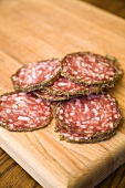 Several slices of salami on a wooden board