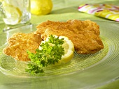 Wiener schnitzel (breaded veal escalopes) with lemon & parsley on glass plate