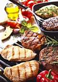 Various meats on barbecue and in grill frying pan