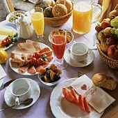 Üppig gedeckter Frühstückstisch mit Säften, Aufschnitt & Obst