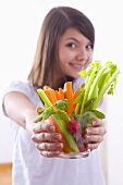 Girl holding a bowl of vegetable sticks with radishes