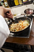 Preparing Asian noodles with vegetables on a gas cooker