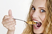 Young woman with a spoonful of cornflakes