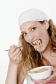 Junge Frau mit Kopftuch frisst Spaghetti