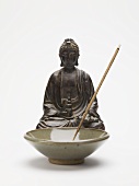 Räucherstäbchen in Keramikschale vor Buddhafigur