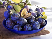 Plums in dish and on branch