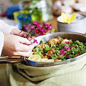 Woman scattering edible flowers over cooked food